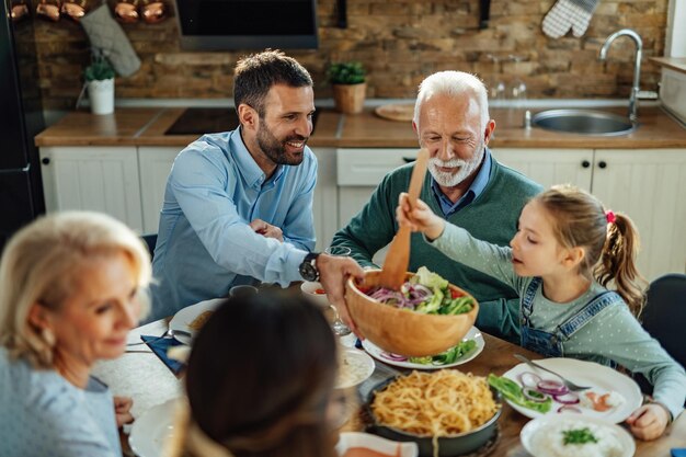 Famiglia allargata felice che pranza e mangia cibo sano al tavolo da pranzo