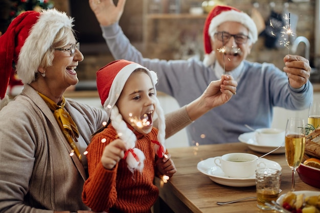 Famiglia allargata gioiosa che usa le stelle filanti durante il pranzo di Natale a casa