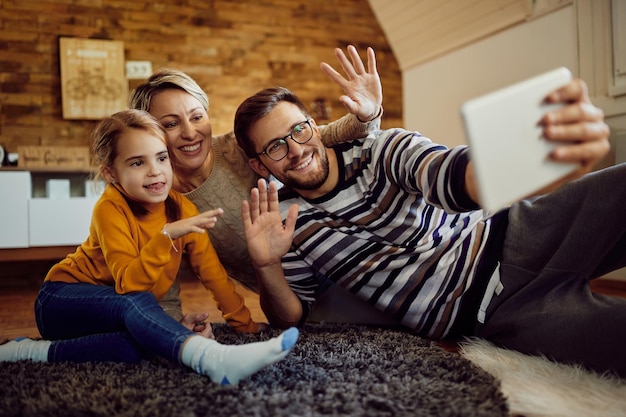 Famiglia allegra che saluta mentre fa una videochiamata sul touchpad a casa