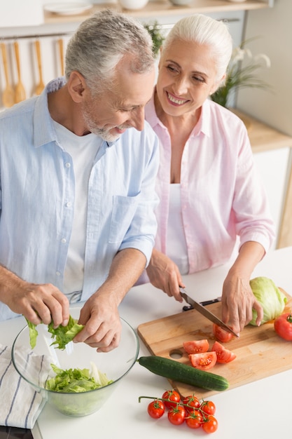 Famiglia amorosa matura felice delle coppie che cucina insalata