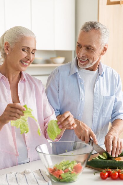 Famiglia amorosa matura felice delle coppie che cucina insalata