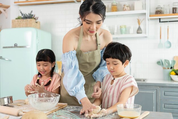 Famiglia asiatica felice che prepara la pasta e cuoce i biscotti in cucina a casa