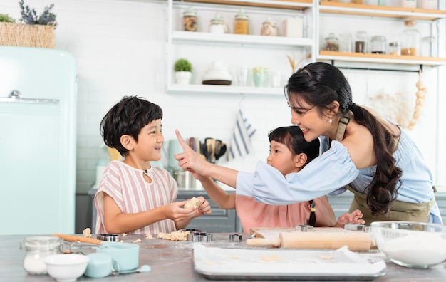 Famiglia asiatica felice che prepara la pasta e cuoce i biscotti in cucina a casa