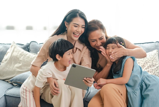 Famiglia asiatica felice che utilizza la tavoletta digitale nel vivere a casa rilassandosi a casa per il concetto di stile di vita