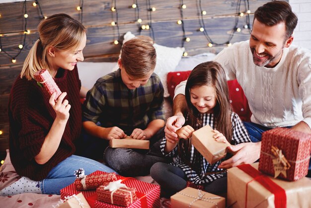 Famiglia che apre i regali di Natale nel letto