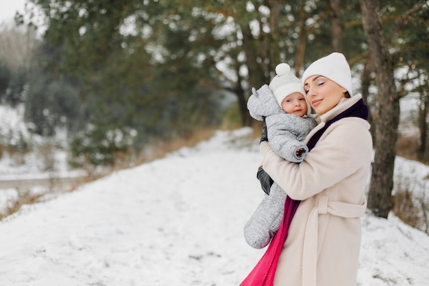 Famiglia che cammina nella neve divertendosi a winter park in una giornata luminosa abbracciati e sorridenti