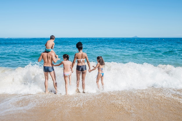 Famiglia che camminano insieme verso l&#39;acqua