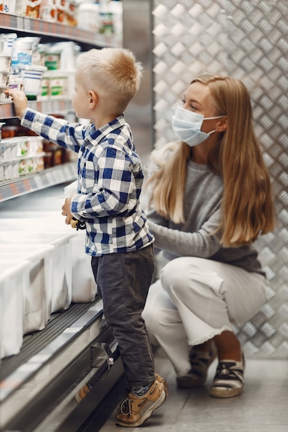 Famiglia che compra generi alimentari. Madre in maglione grigio. Donna in una maschera medica. Tema Coronavirus.