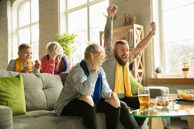 Famiglia che incoraggia e guarda la tv a casa in salotto