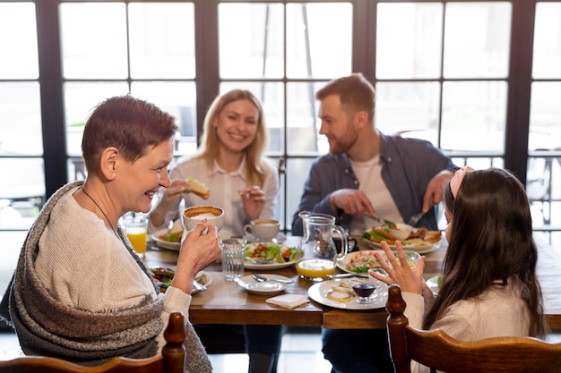 Famiglia che mangia insieme al colpo medio del tavolo