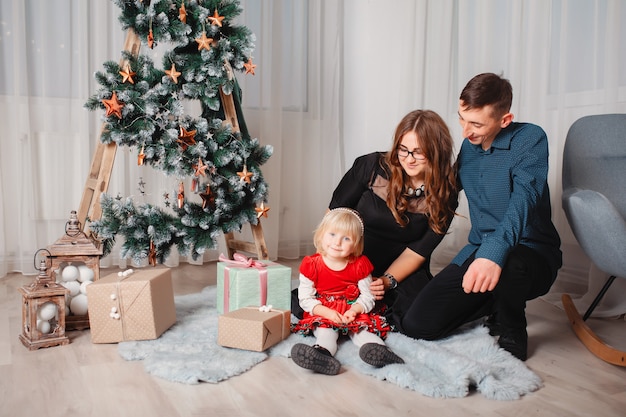 Famiglia che si siede a casa vicino all'albero di Natale