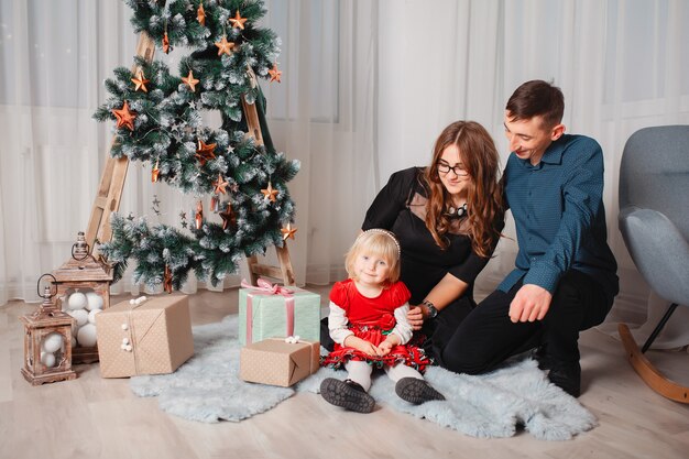 Famiglia che si siede a casa vicino all'albero di Natale