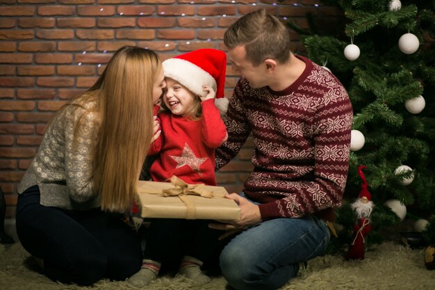 Famiglia che si siede dall&#39;albero di Natale con i regali dell&#39;imballaggio della piccola figlia