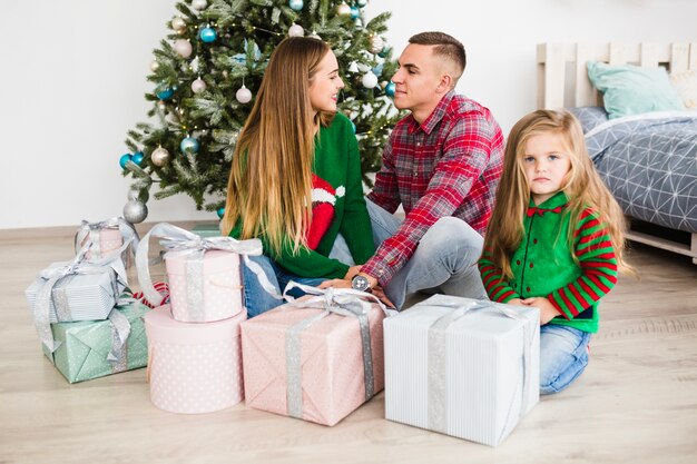 Famiglia con doni davanti all&#39;albero di Natale