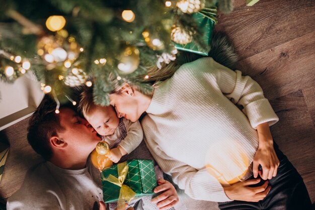 Famiglia con la figlia del bambino sotto l'albero di Natale