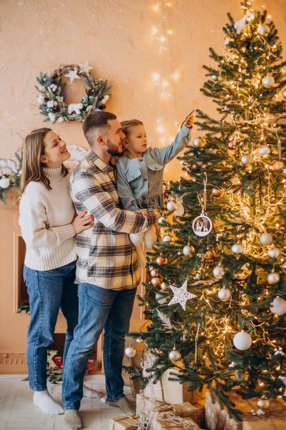 Famiglia con la piccola figlia insieme all'albero di Natale