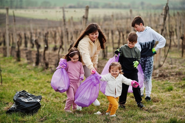 Famiglia con sacco della spazzatura che raccoglie immondizia durante la pulizia nei vigneti Conservazione ambientale e riciclaggio ecologico