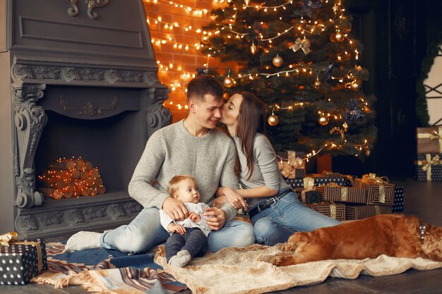 Famiglia con simpatico cane a casa vicino all'albero di Natale