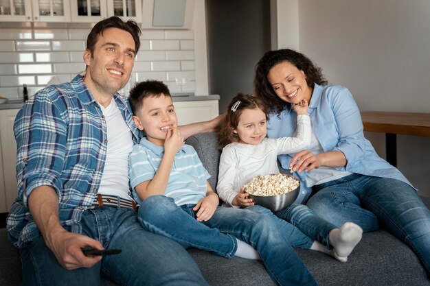 Famiglia del colpo medio che guarda la televisione