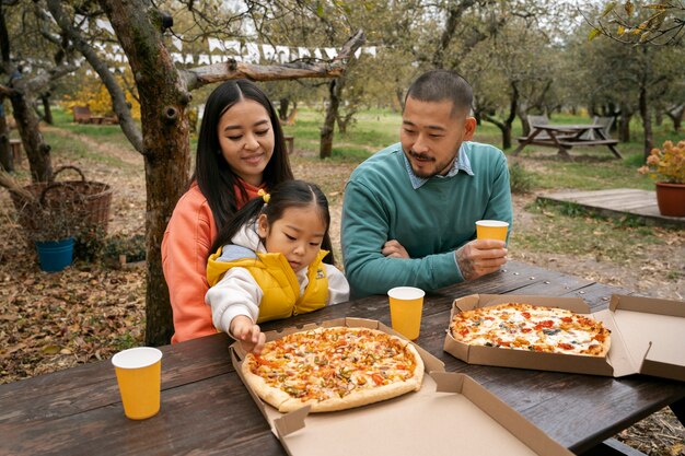 Famiglia del piano medio che mangia pizza all'aperto