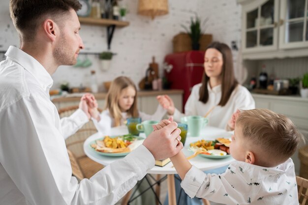 Famiglia di tiro medio che prega a tavola