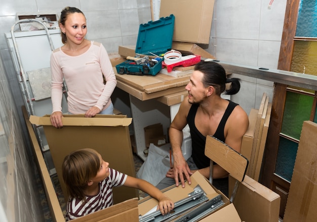 Famiglia disimballo scatole con nuovi mobili