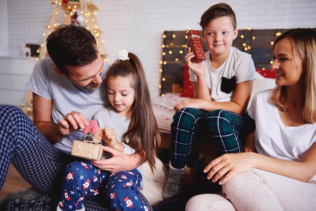 Famiglia felice che apre i regali di Natale a letto