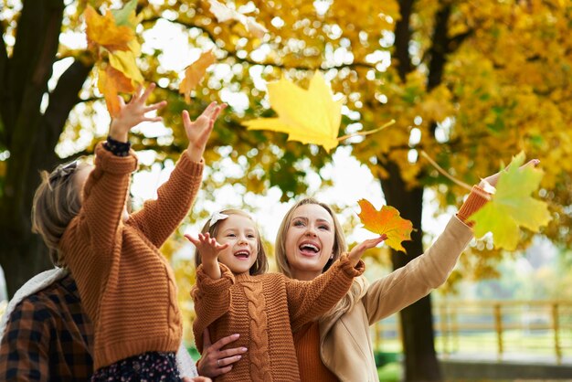 Famiglia felice che cattura foglie autunnali