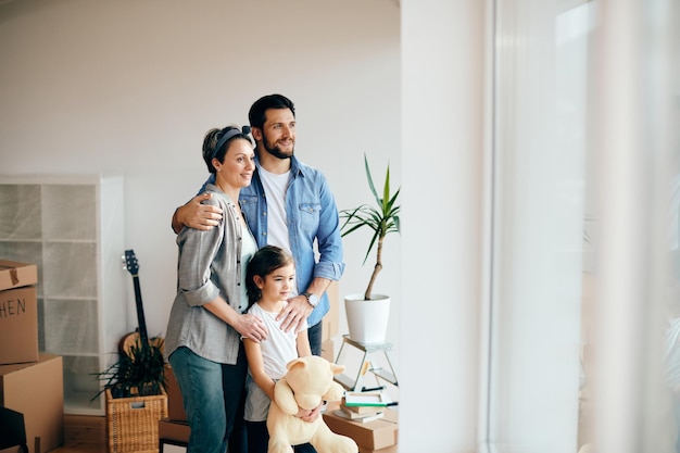 Famiglia felice che guarda attraverso la finestra mentre si trasferisce in una nuova casa