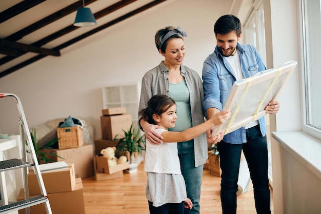 Famiglia felice che guarda la pittura avvolta mentre si trasferisce nella nuova casa