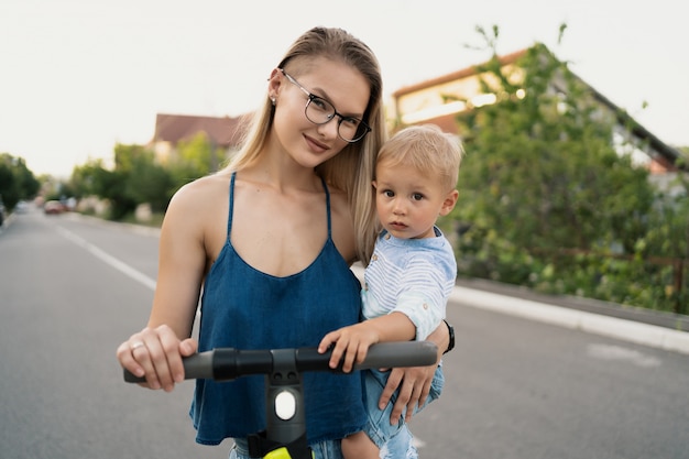 Famiglia felice che guida scooter nel quartiere sulla strada.