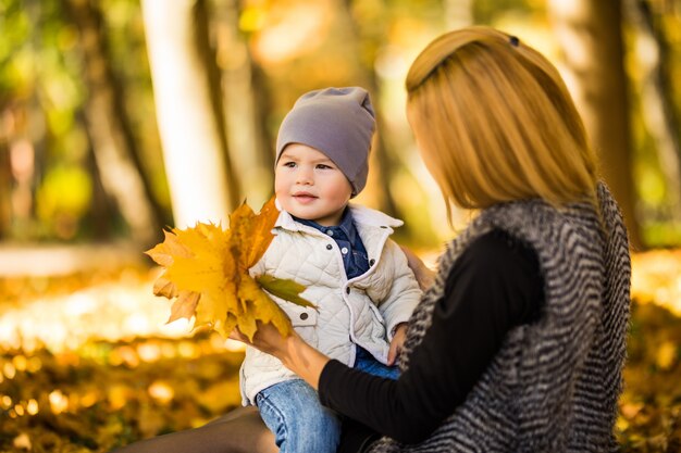 Famiglia felice che ha divertimento all'aperto nel parco di autunno contro foglie sfocate