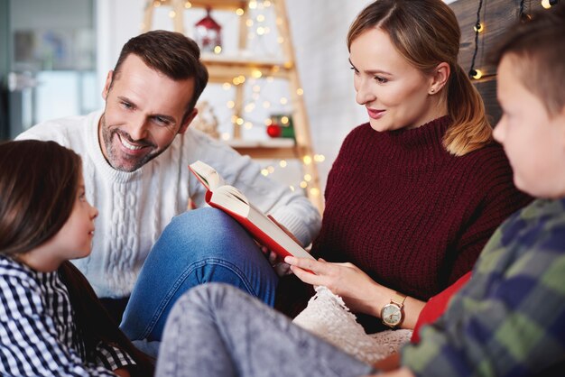 Famiglia felice che legge un libro nel periodo natalizio