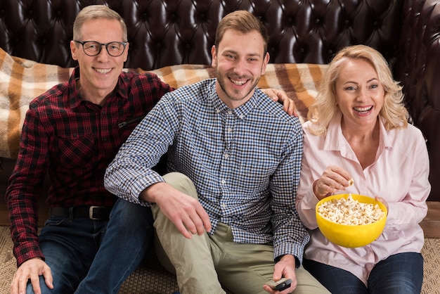 Famiglia felice che propone con la ciotola di popcorn