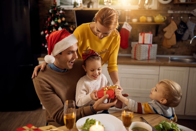 Famiglia felice che si diverte mentre apre i regali di Natale a casa
