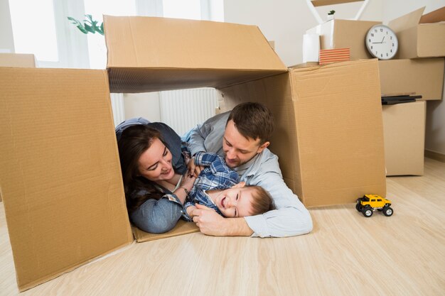 Famiglia felice che si trova all&#39;interno della scatola di cartone a casa