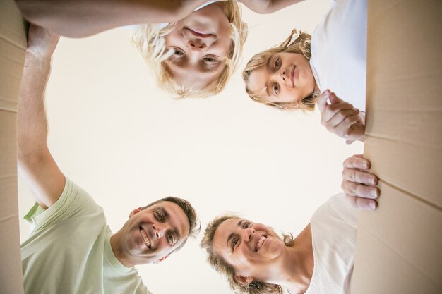 Famiglia felice con bambini carini che aprono una scatola di cartone in movimento e guardano dentro