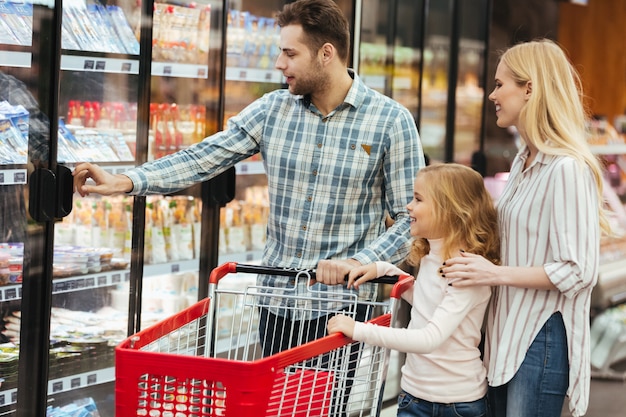 Famiglia felice con cibo d'acquisto del carrello e del bambino