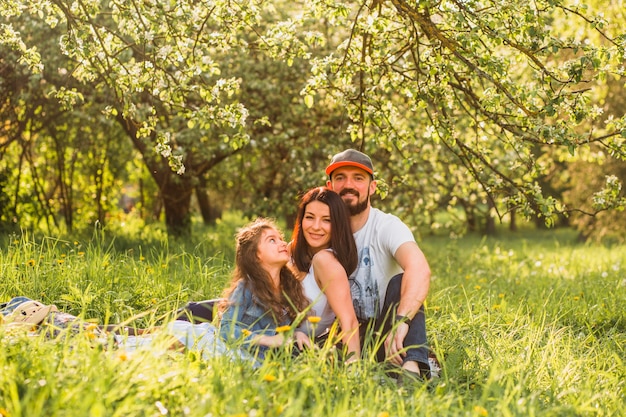 Famiglia felice con la figlia che si siede nel parco