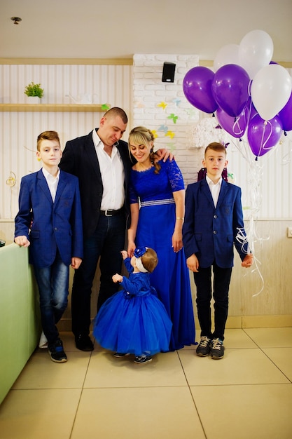 Famiglia felice con la piccola neonata sveglia al giorno di compleanno di 1 anno del vestito blu