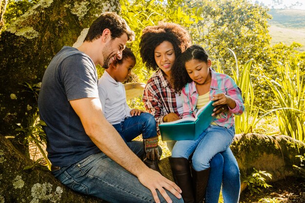 Famiglia felice di leggere insieme sotto un albero