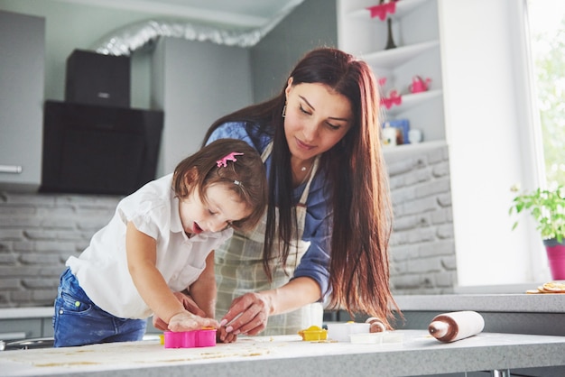 Famiglia felice in cucina. Concetto di cibo per le vacanze. La madre e la figlia che preparano la pasta, cuociono i biscotti. Famiglia felice nella produzione di biscotti a casa. Cibo fatto in casa e piccolo aiuto