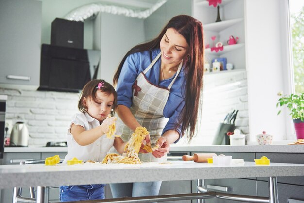 Famiglia felice in cucina. La madre e la figlia che preparano la pasta, cuociono i biscotti.