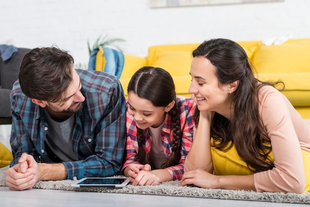 Famiglia felice seduto su un piano e guardando un cellulare