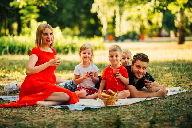 Famiglia felice su una coperta che beve succo