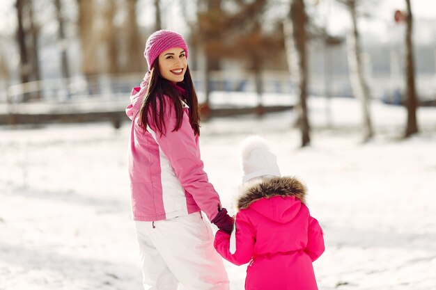 Famiglia in cappelli invernali lavorati a maglia in vacanza di Natale in famiglia. Donna e bambina in un parco. Persone che giocano.