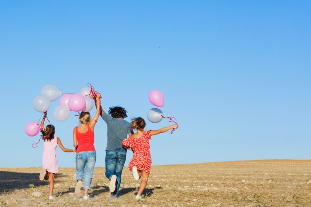 Famiglia in esecuzione in campo con palloncini