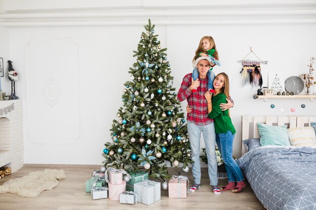 Famiglia in piedi accanto all&#39;albero di Natale