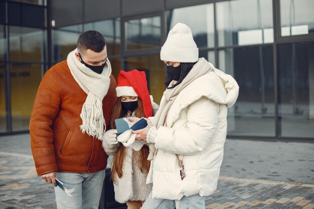 Famiglia in piedi all'aperto indossando maschera facciale e controllando i passaporti