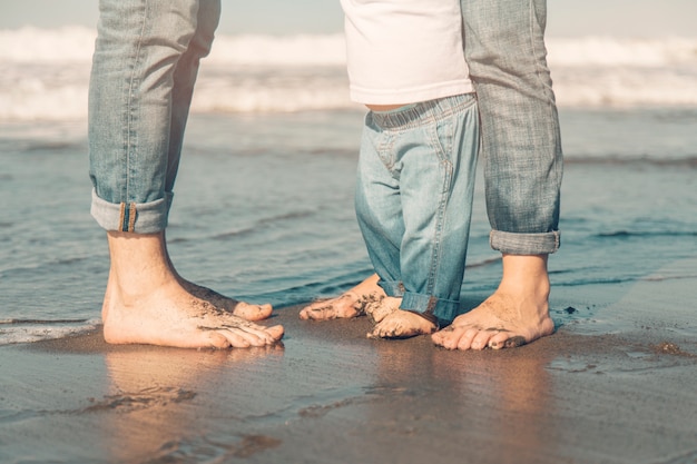 Famiglia in piedi sulla sabbia dal mare